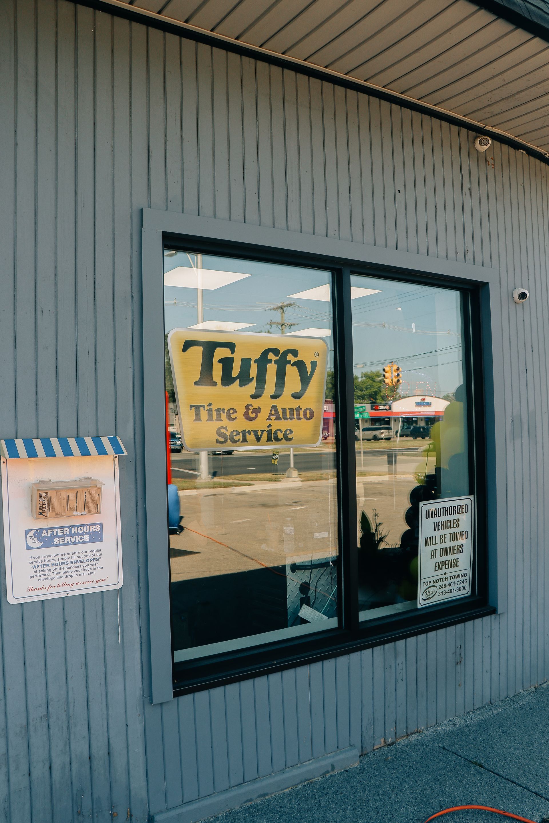 Exterior of a Tuffy Tire & Auto Service business with a sign in the window; a mailbox is to the left.