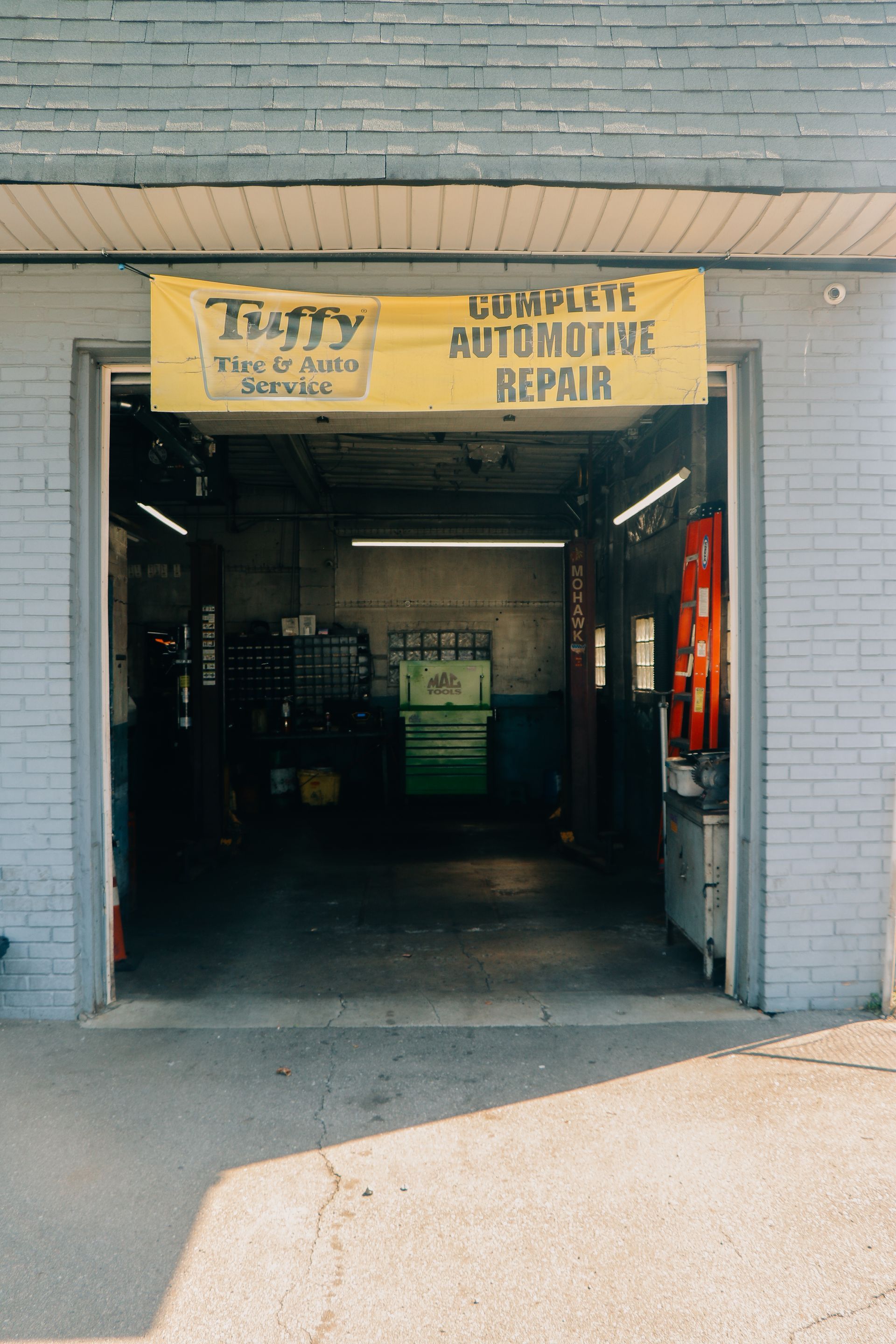 An auto repair shop with an open garage door and a banner that says 