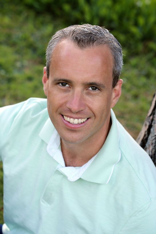 A woman is sitting at a desk with a laptop and a vase of flowers.