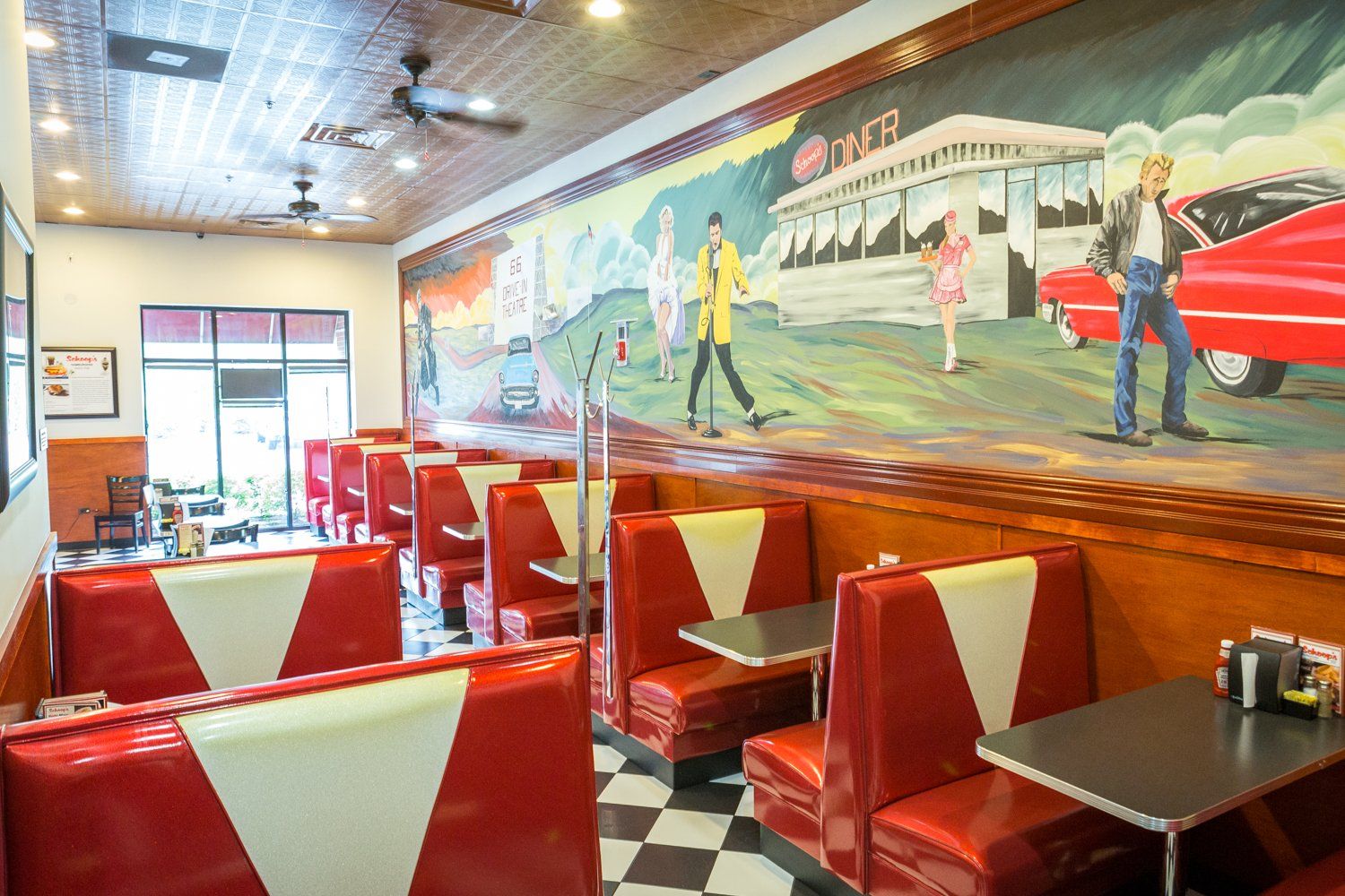 A diner with red and white booths and a mural on the wall.