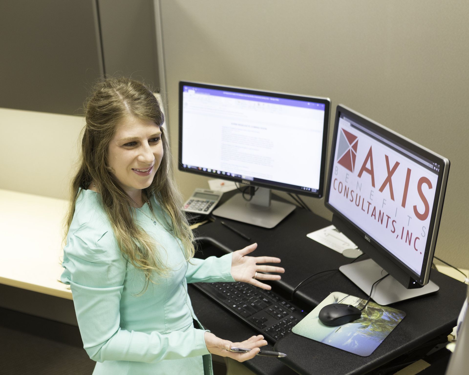 A woman is standing in front of two computer monitors that say axis