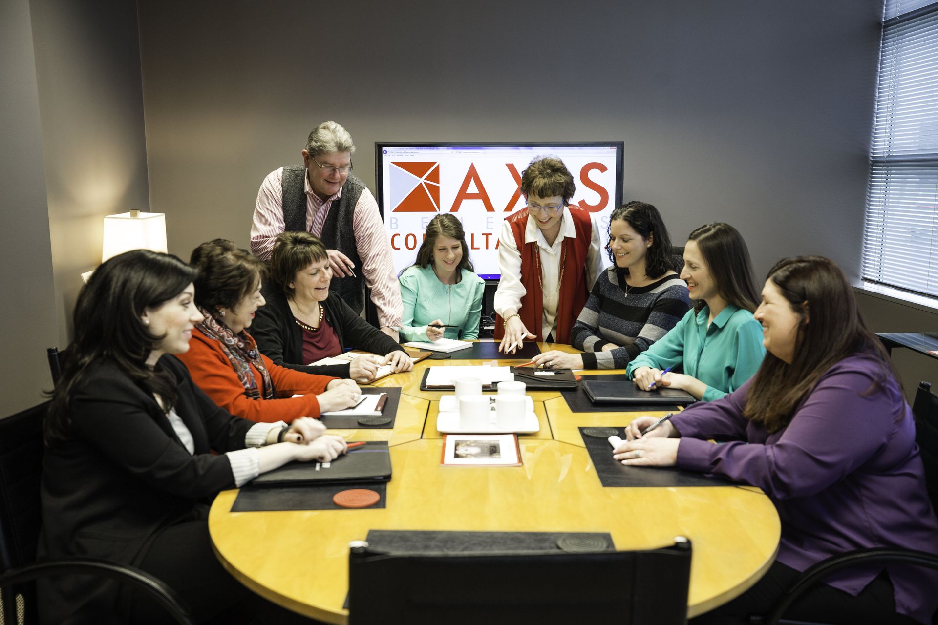 A group of women are sitting around a table in a conference room.
