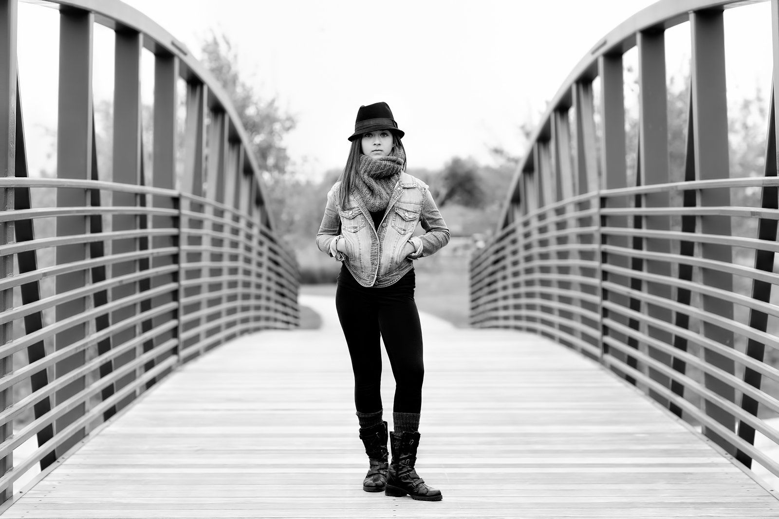 A woman is standing on a bridge in a black and white photo.