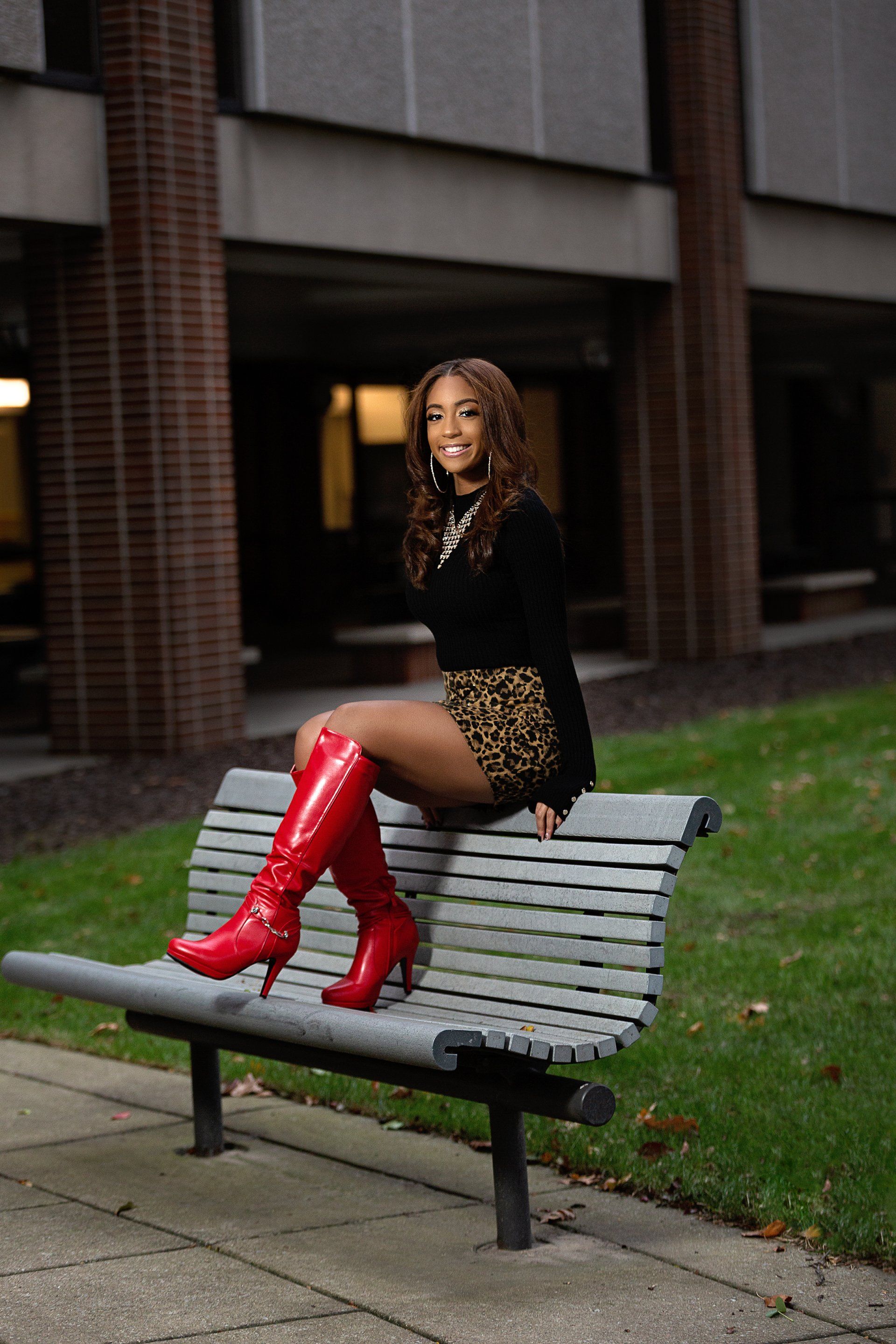 A woman is sitting on a bench wearing red boots.