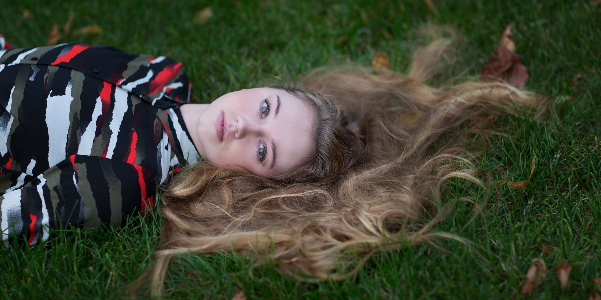 A woman with long hair is laying in the grass.