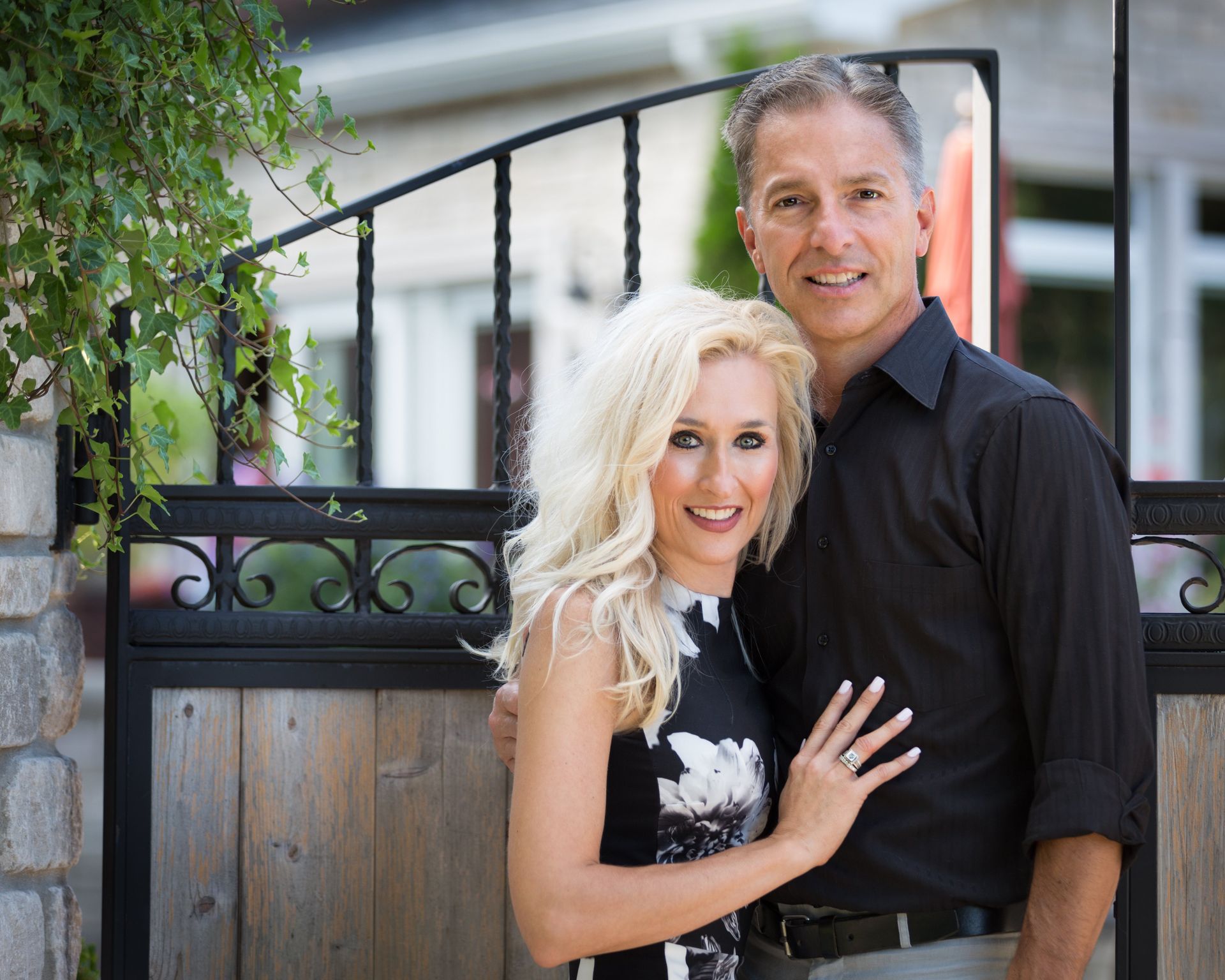 A man and a woman are posing for a picture in front of a gate.