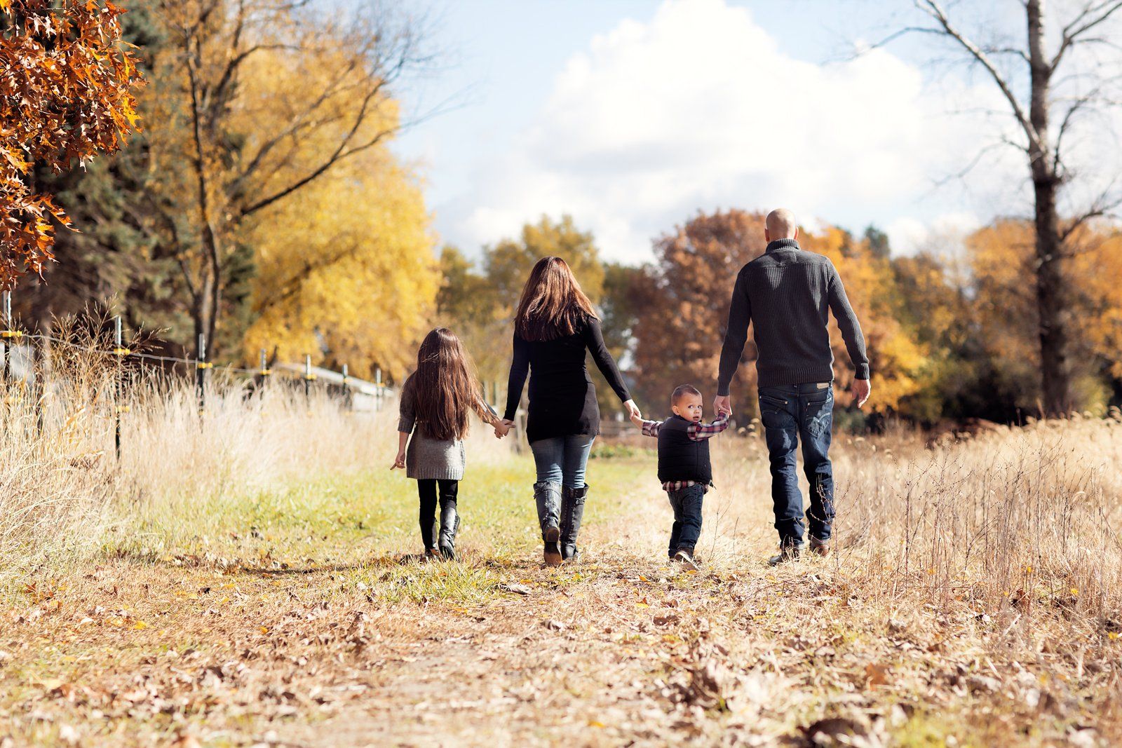 A family is walking through a field holding hands.