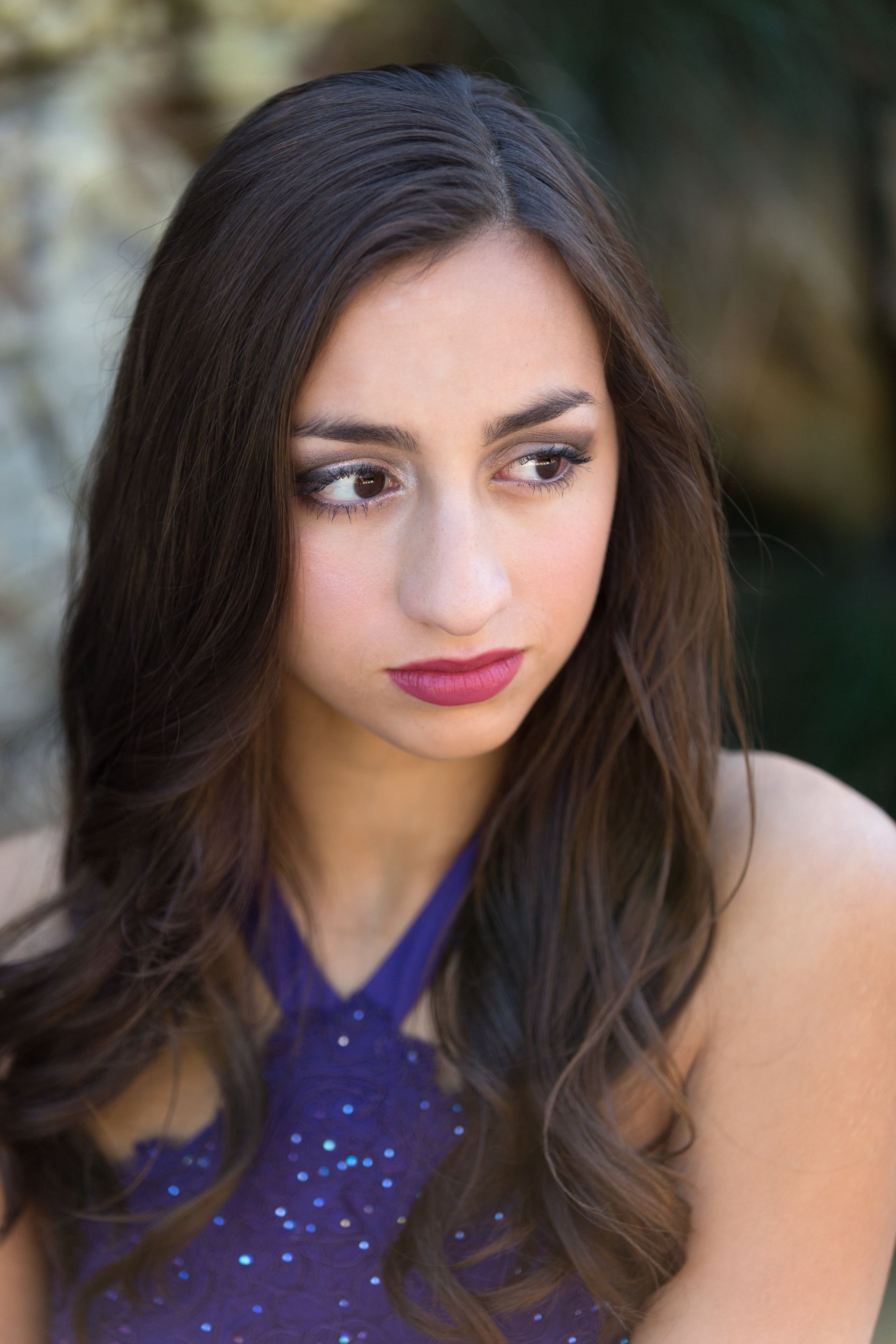 A woman in a purple dress is looking at the camera.