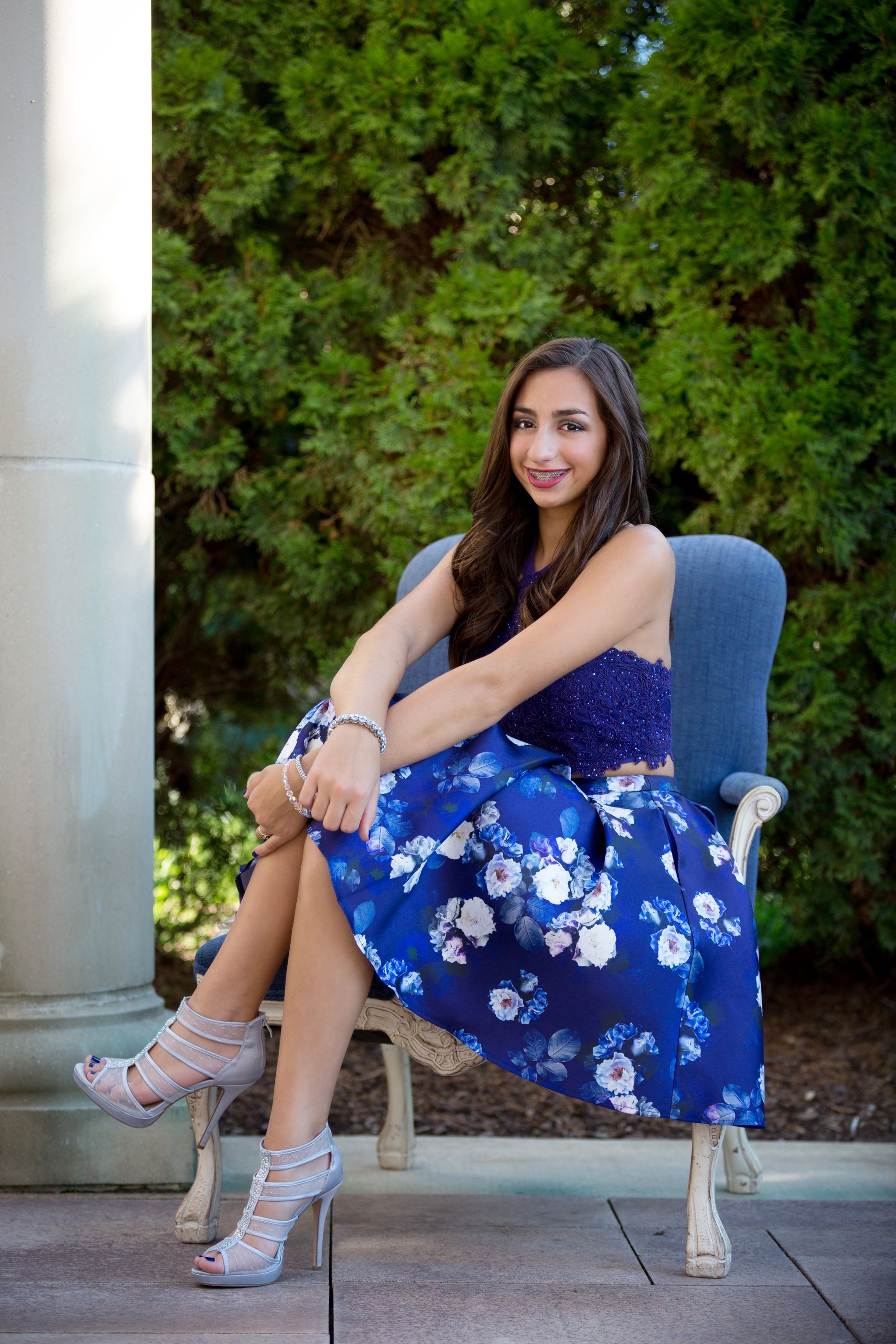 A woman in a blue dress is sitting on a chair.