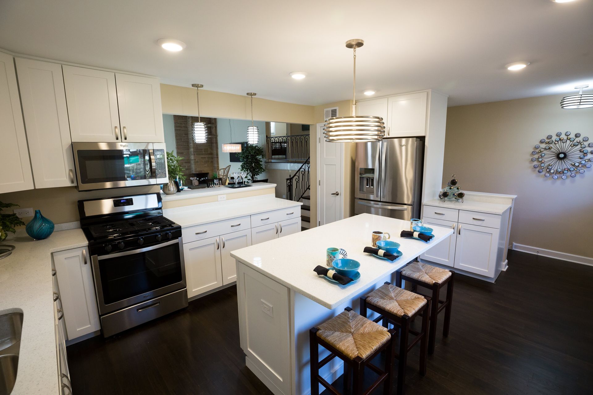 A kitchen with white cabinets , stainless steel appliances , and a large island.