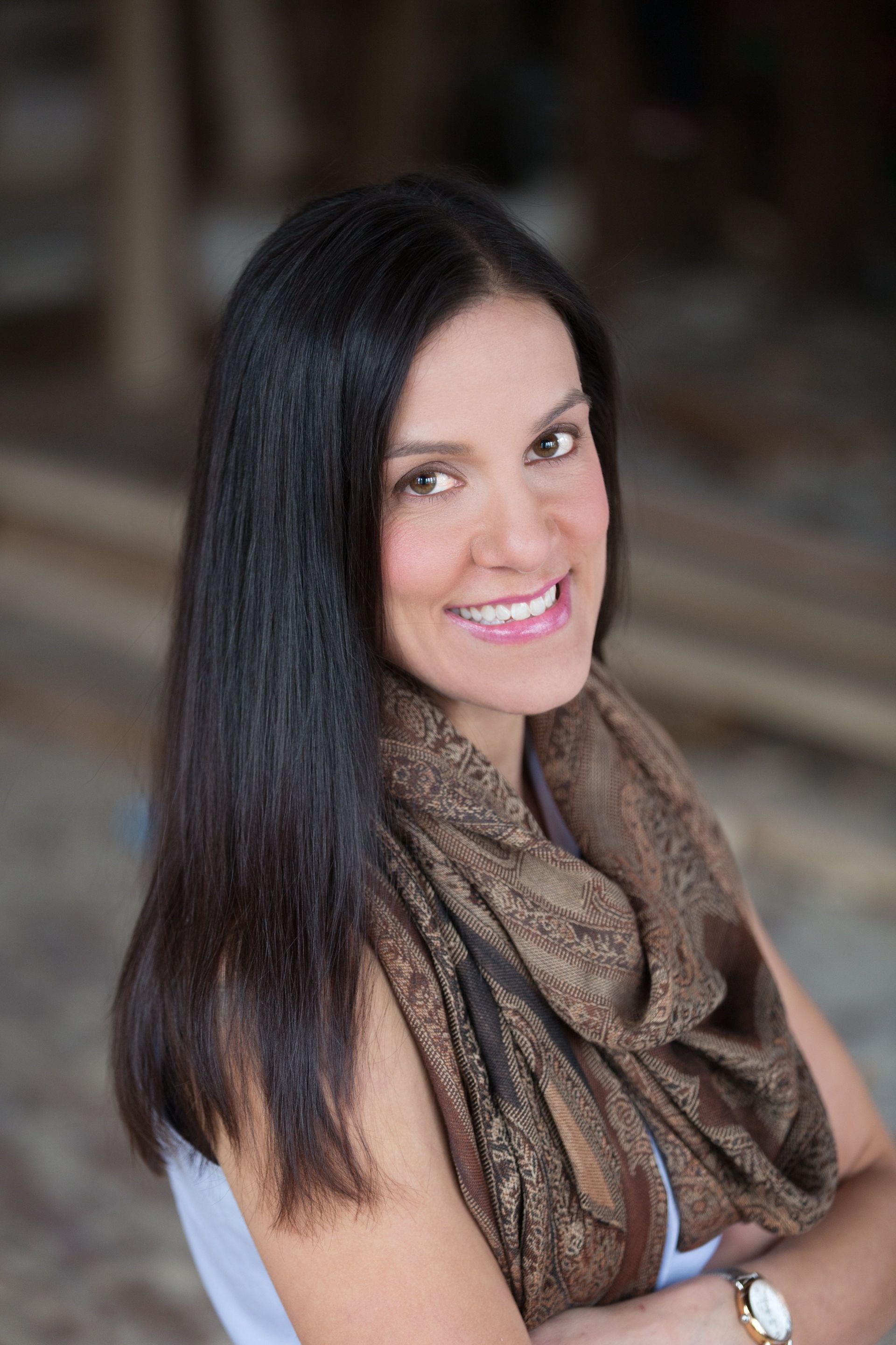 A woman wearing a scarf and a watch is smiling for the camera.