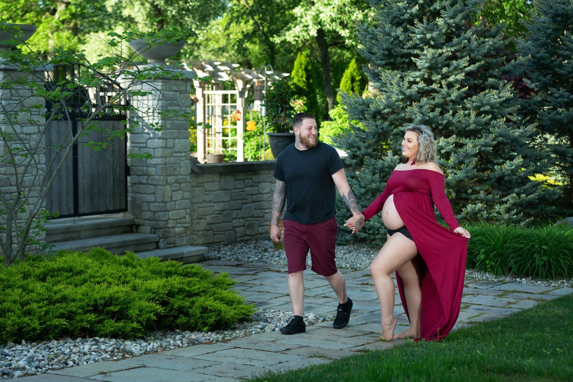 A man and a pregnant woman are holding hands in a garden.