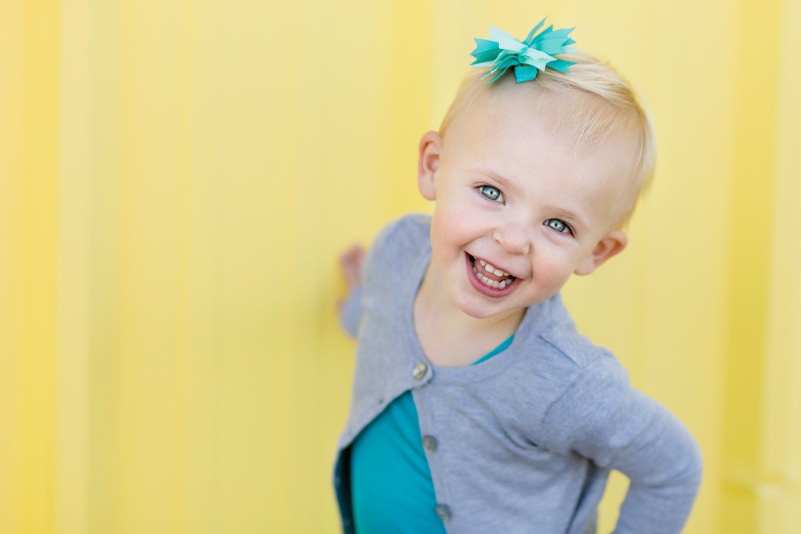 A little girl with a blue bow in her hair is smiling.