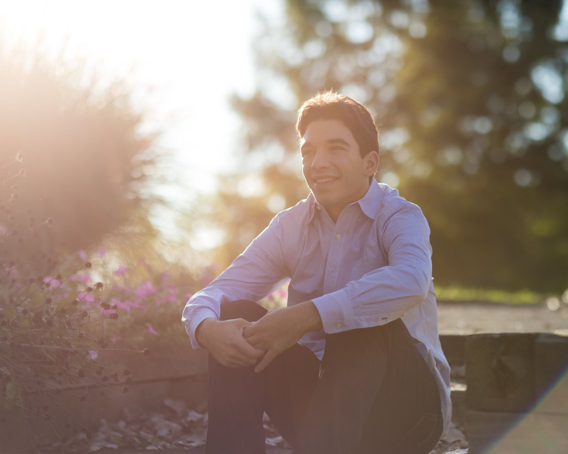 A man is kneeling down in front of a flower bed.