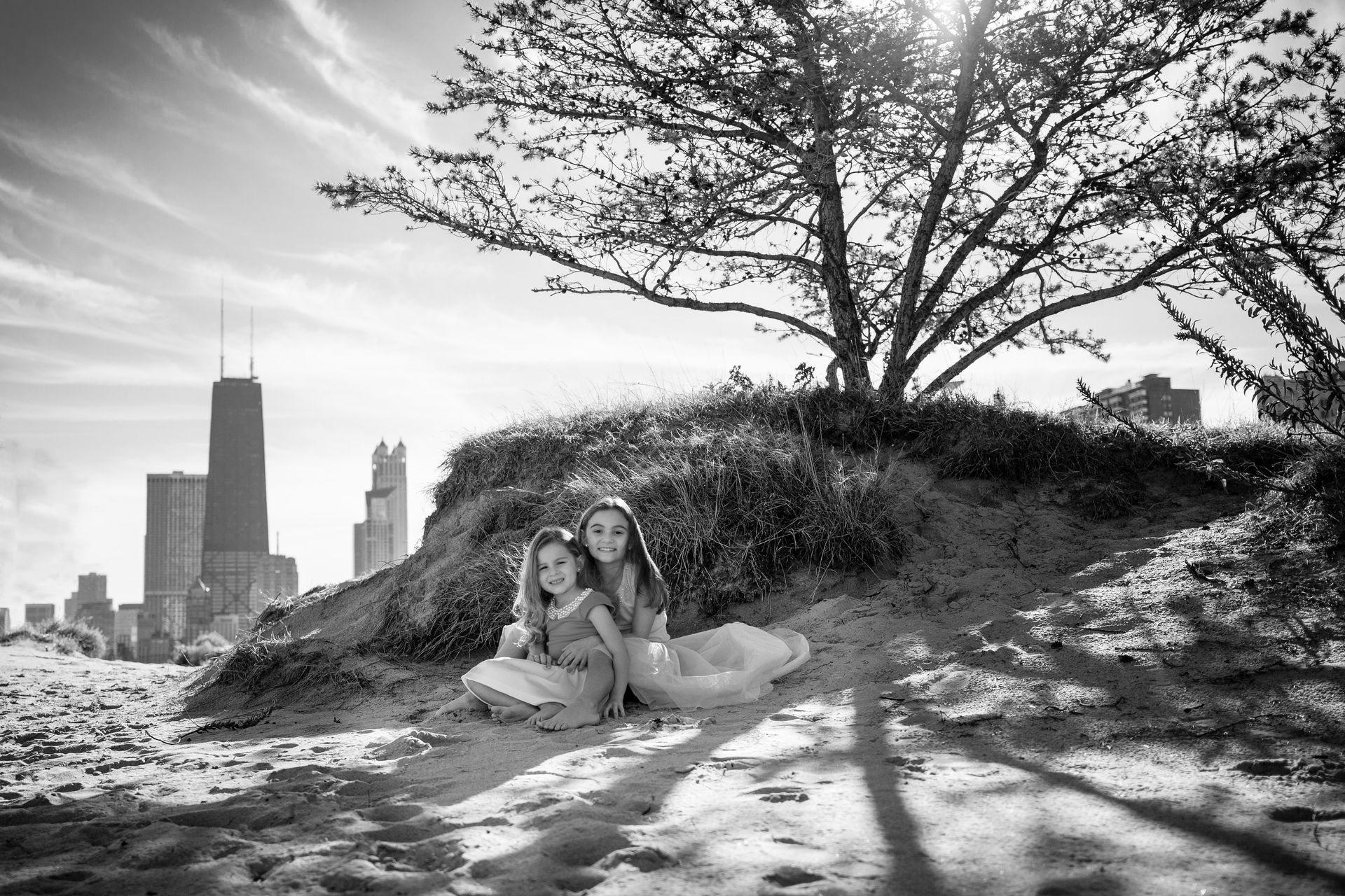A black and white photo of two girls sitting on top of a hill.