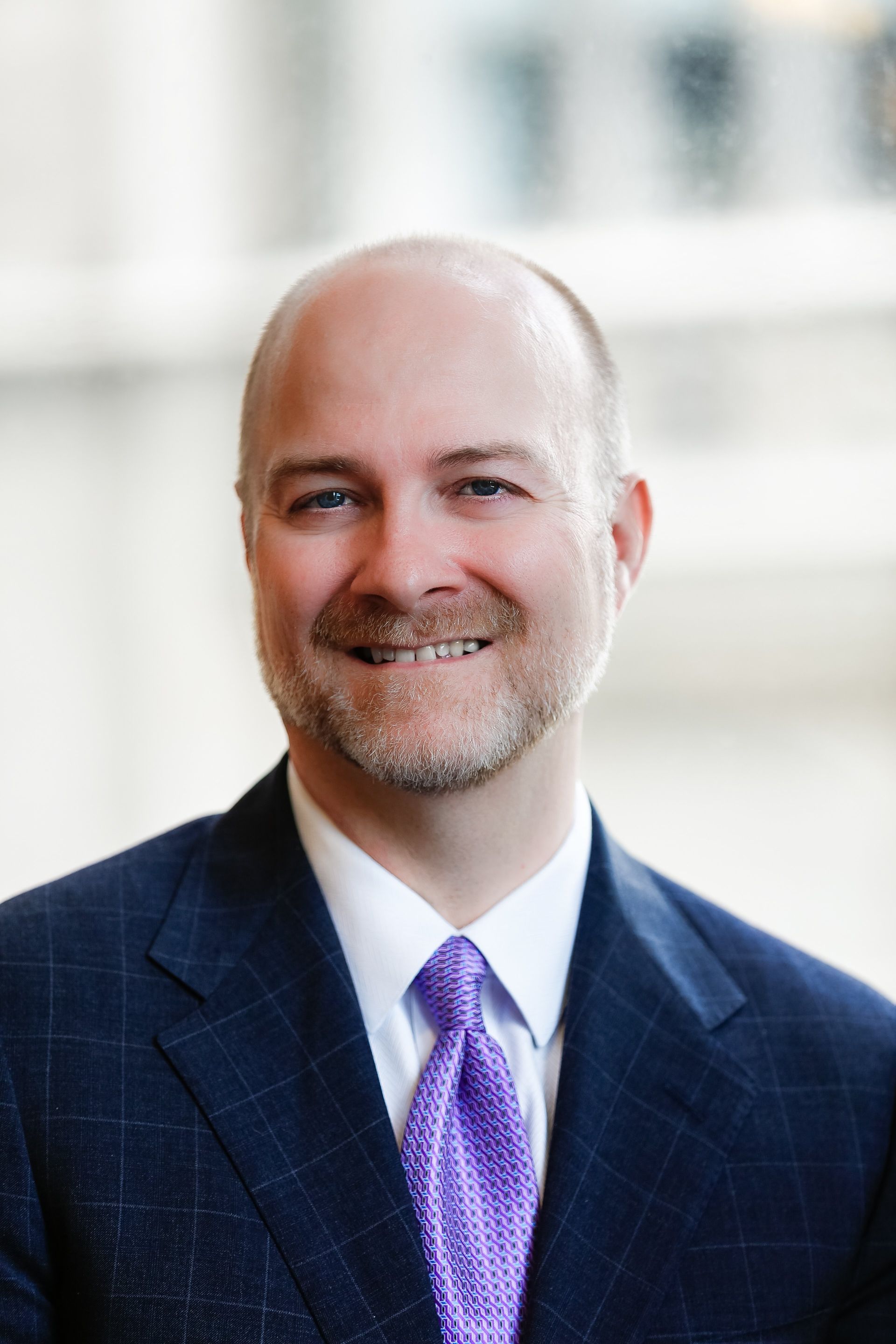A man in a suit and tie is smiling for the camera