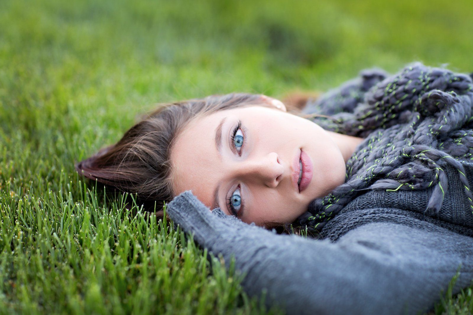 A woman is laying on her stomach in the grass.