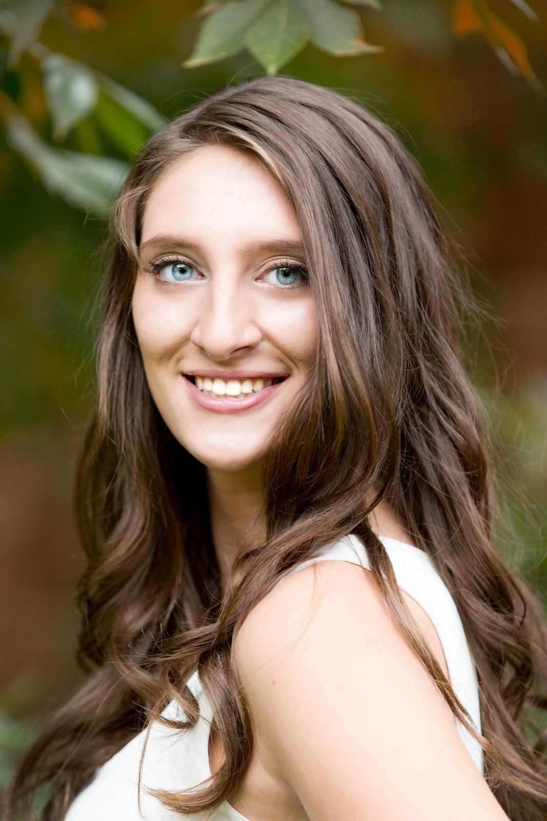 A woman with long brown hair and blue eyes is smiling for the camera.