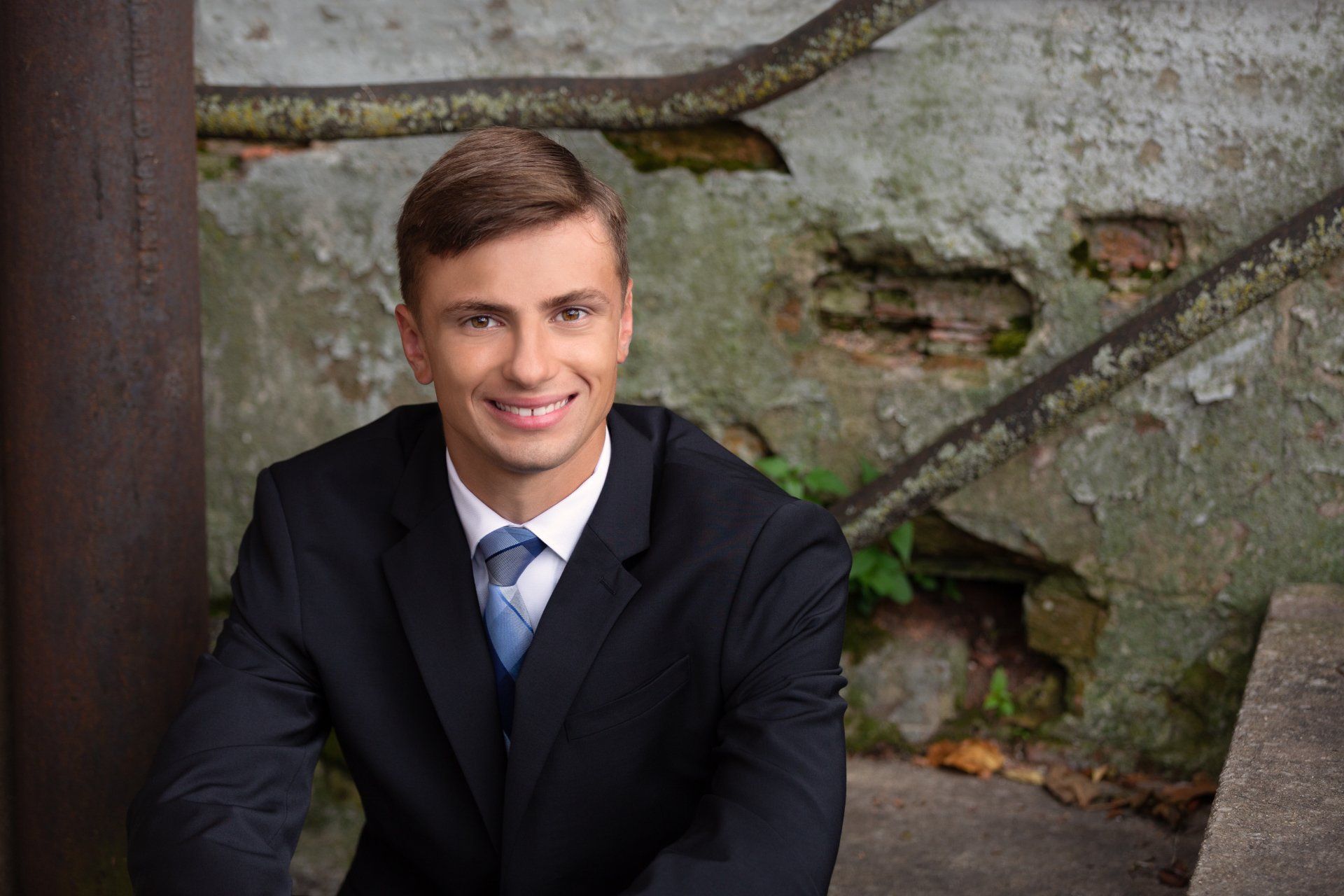 A young man in a suit and tie is sitting on a bench.