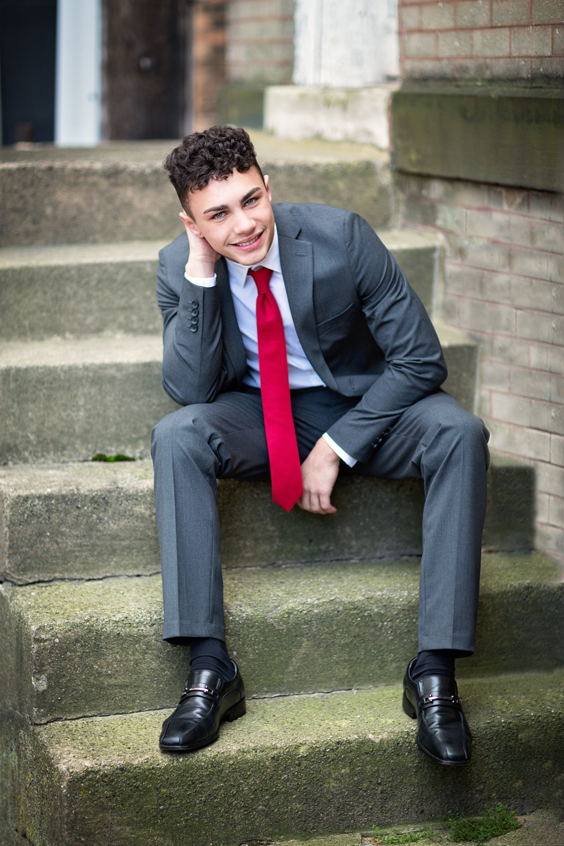 A man in a suit and tie is sitting on a set of stairs.