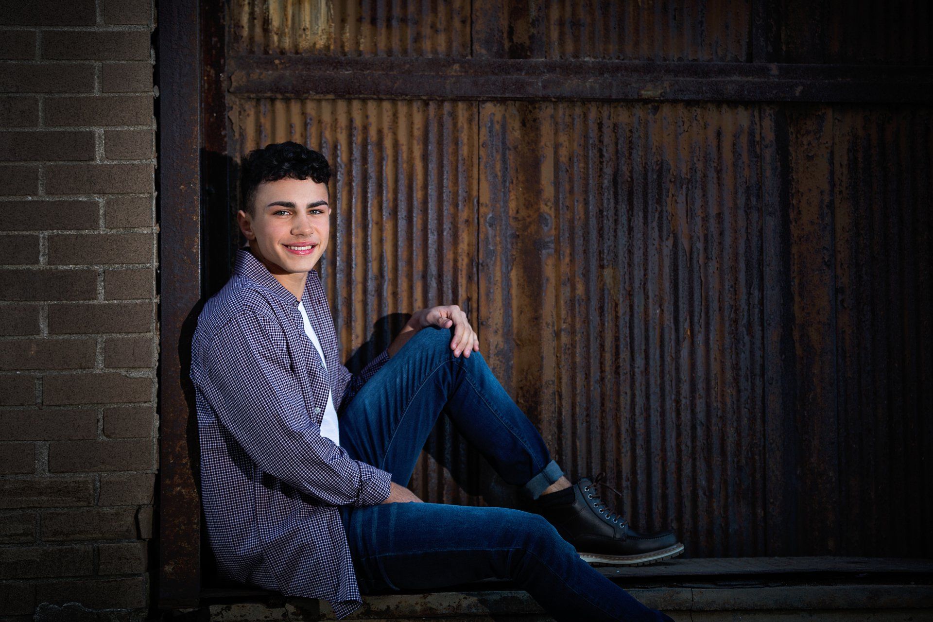 A young man is sitting on the steps of a building.