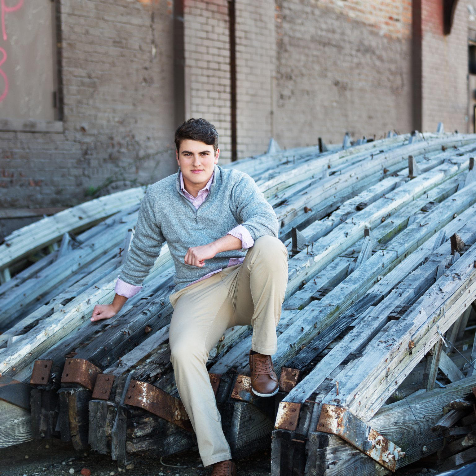 A man is sitting on a pile of wooden beams