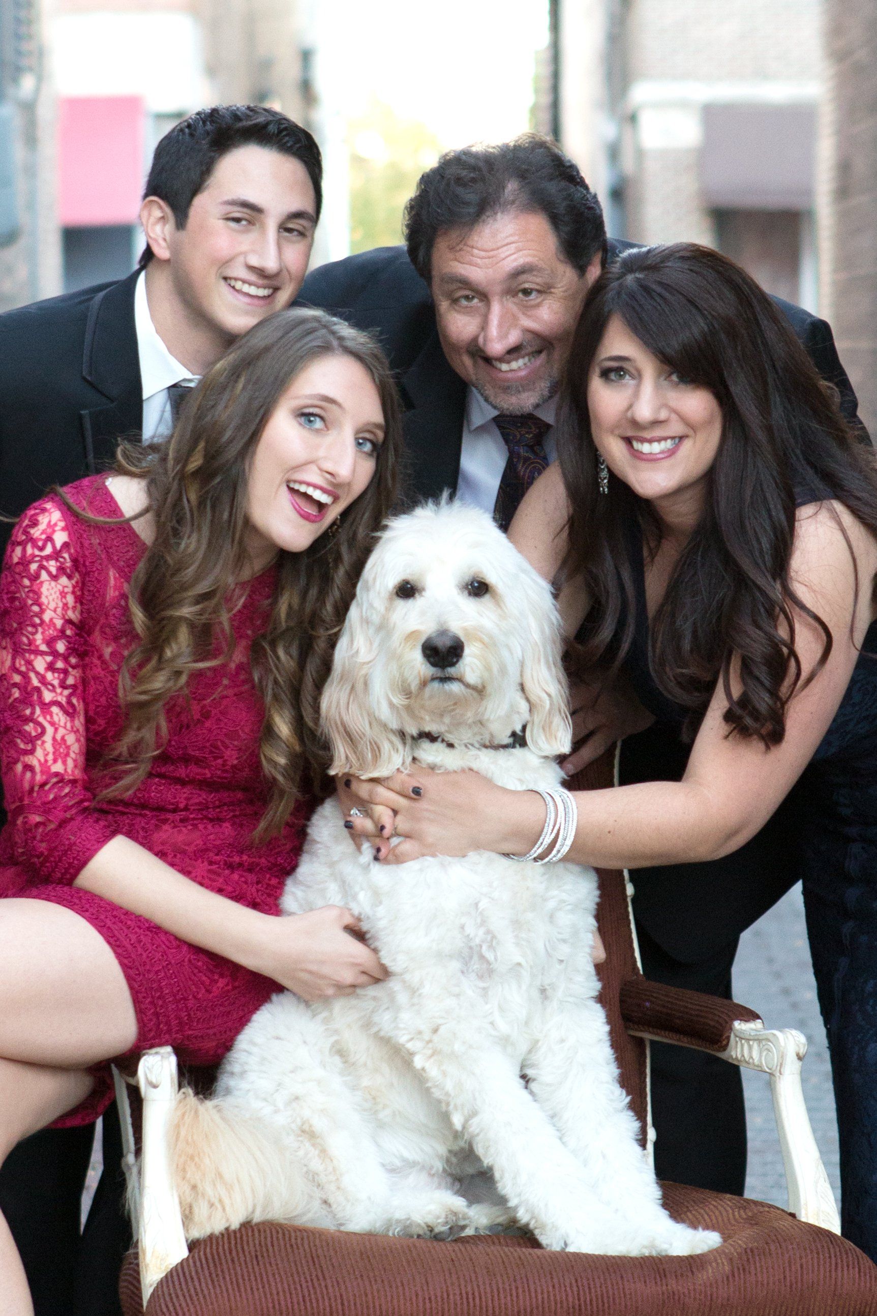 A family is posing for a picture with their dog.