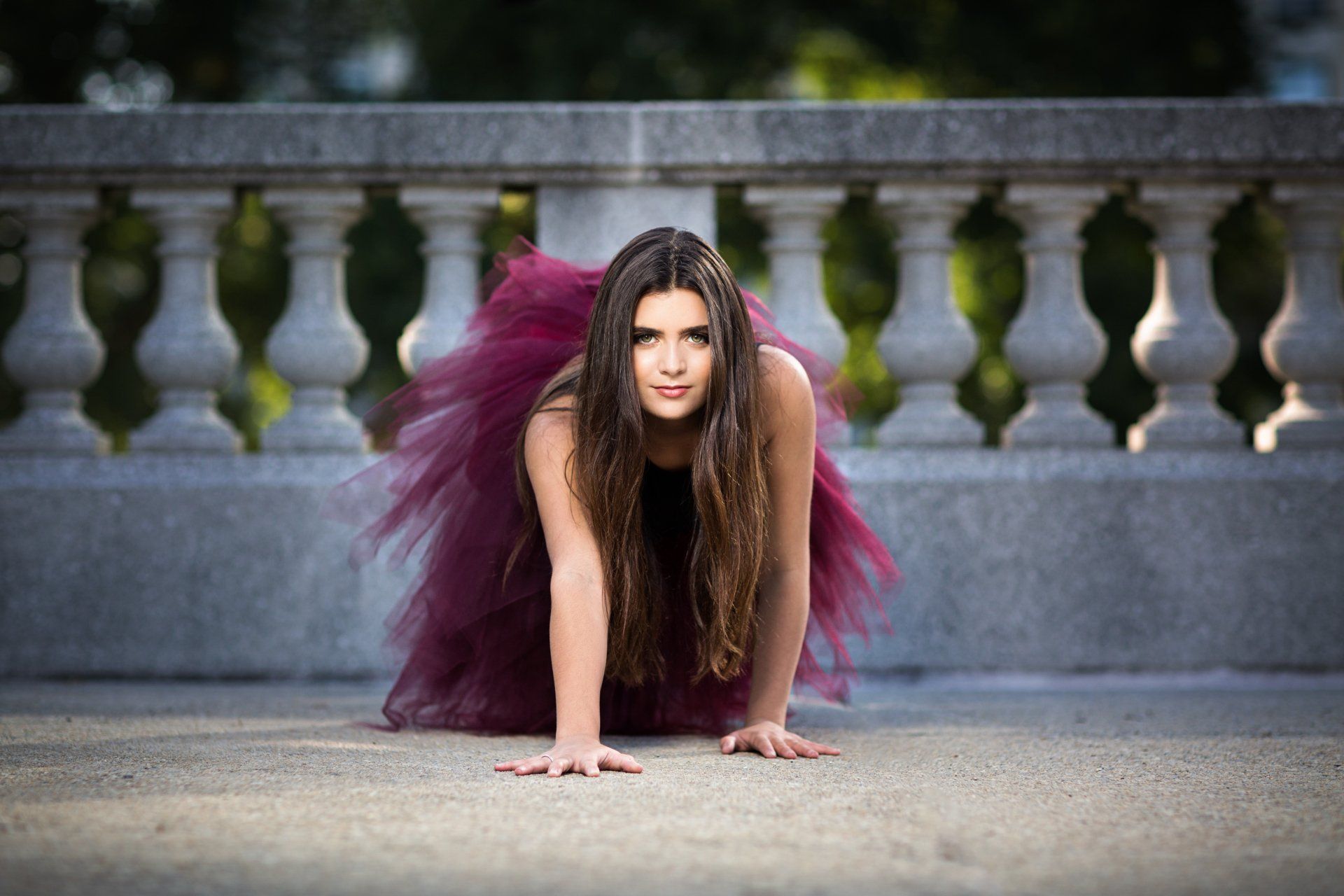 A woman in a purple tutu is crawling on the ground.
