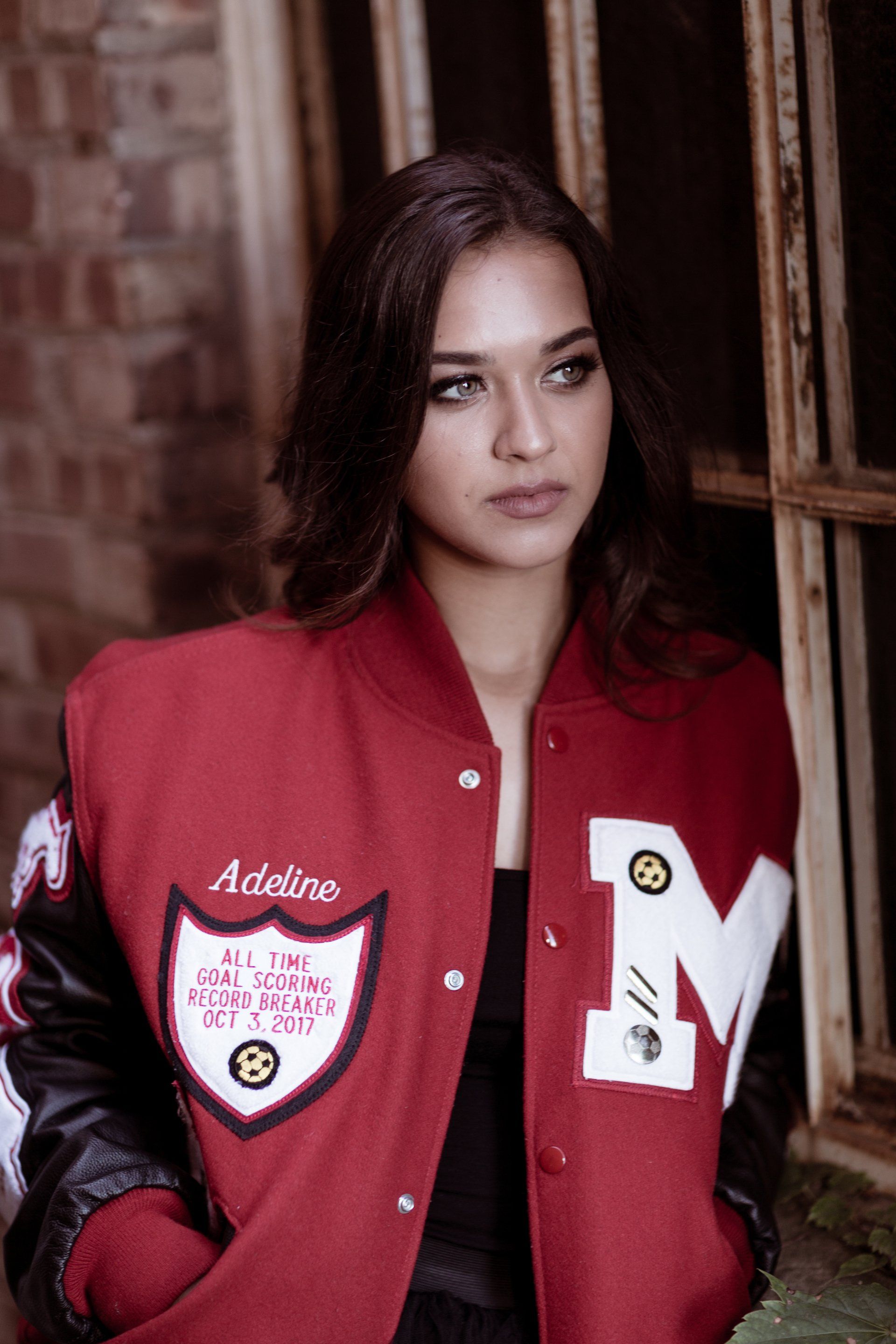 A woman wearing a red and black varsity jacket with the letter m on the sleeves.