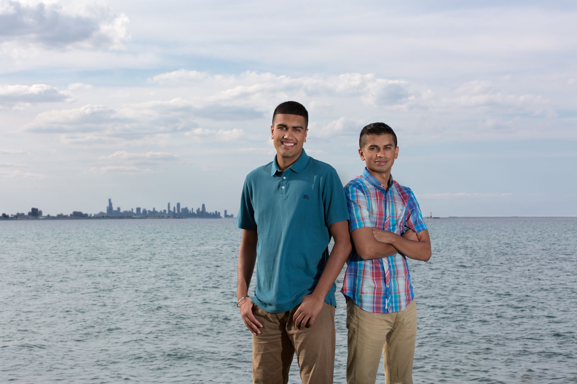 Two young men are standing next to each other on the beach.
