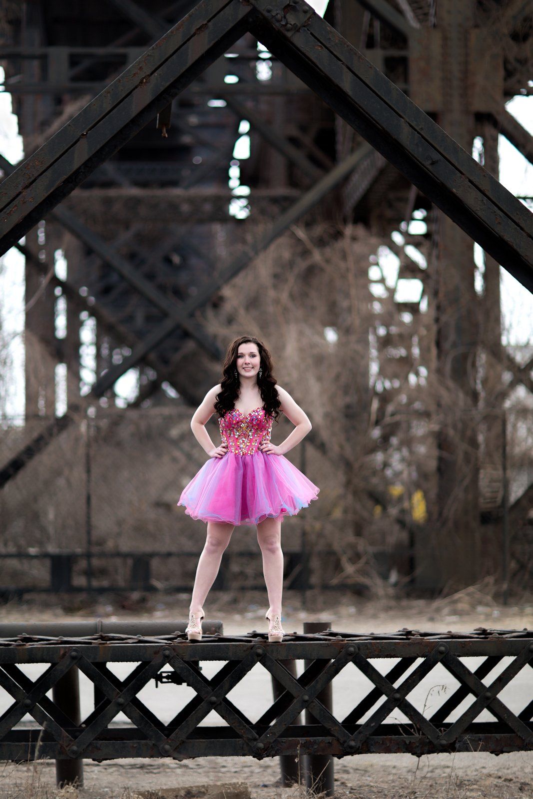 A woman in a pink dress is standing on a bridge.