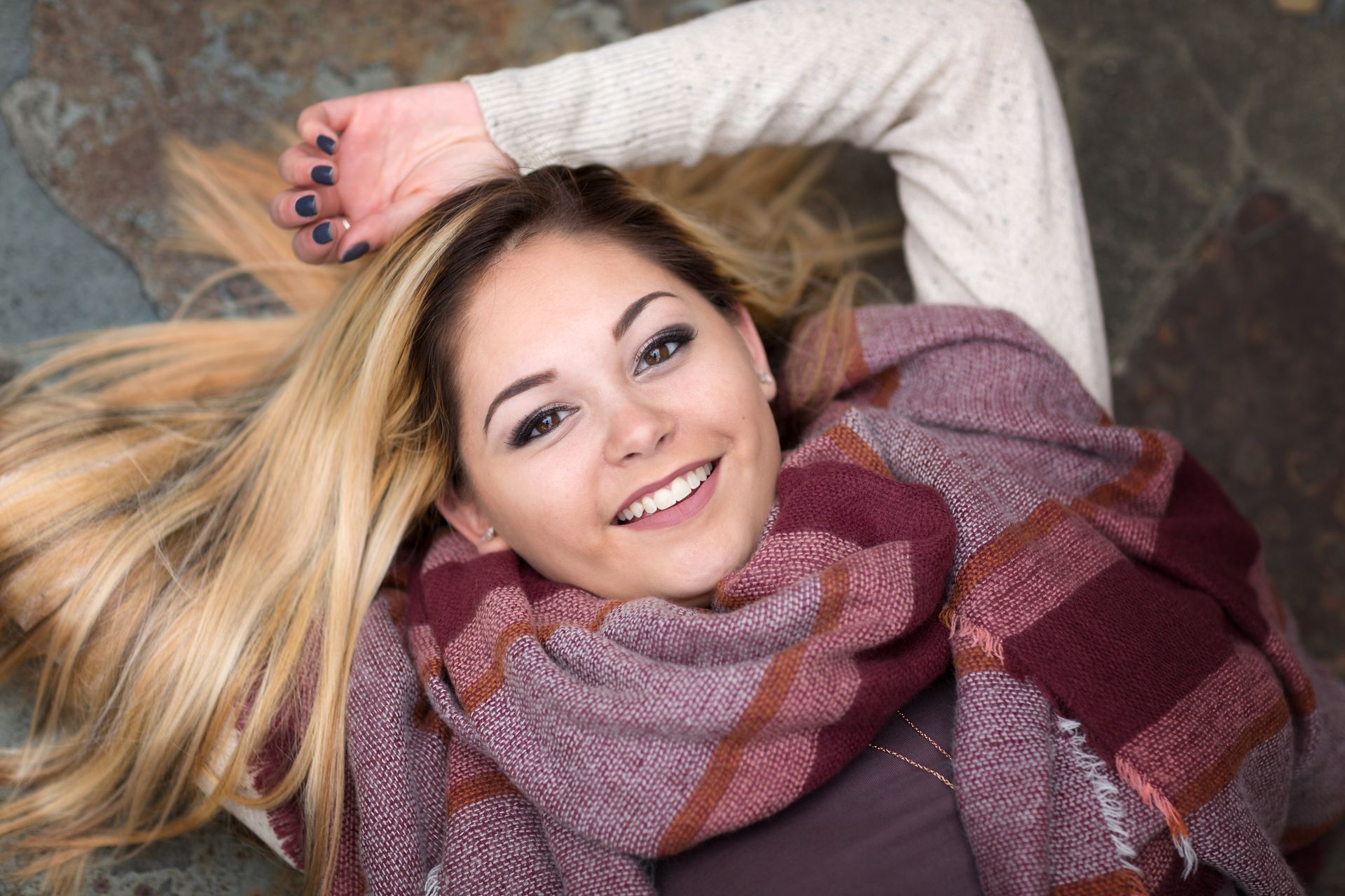 A woman is laying on the floor wearing a scarf and smiling.