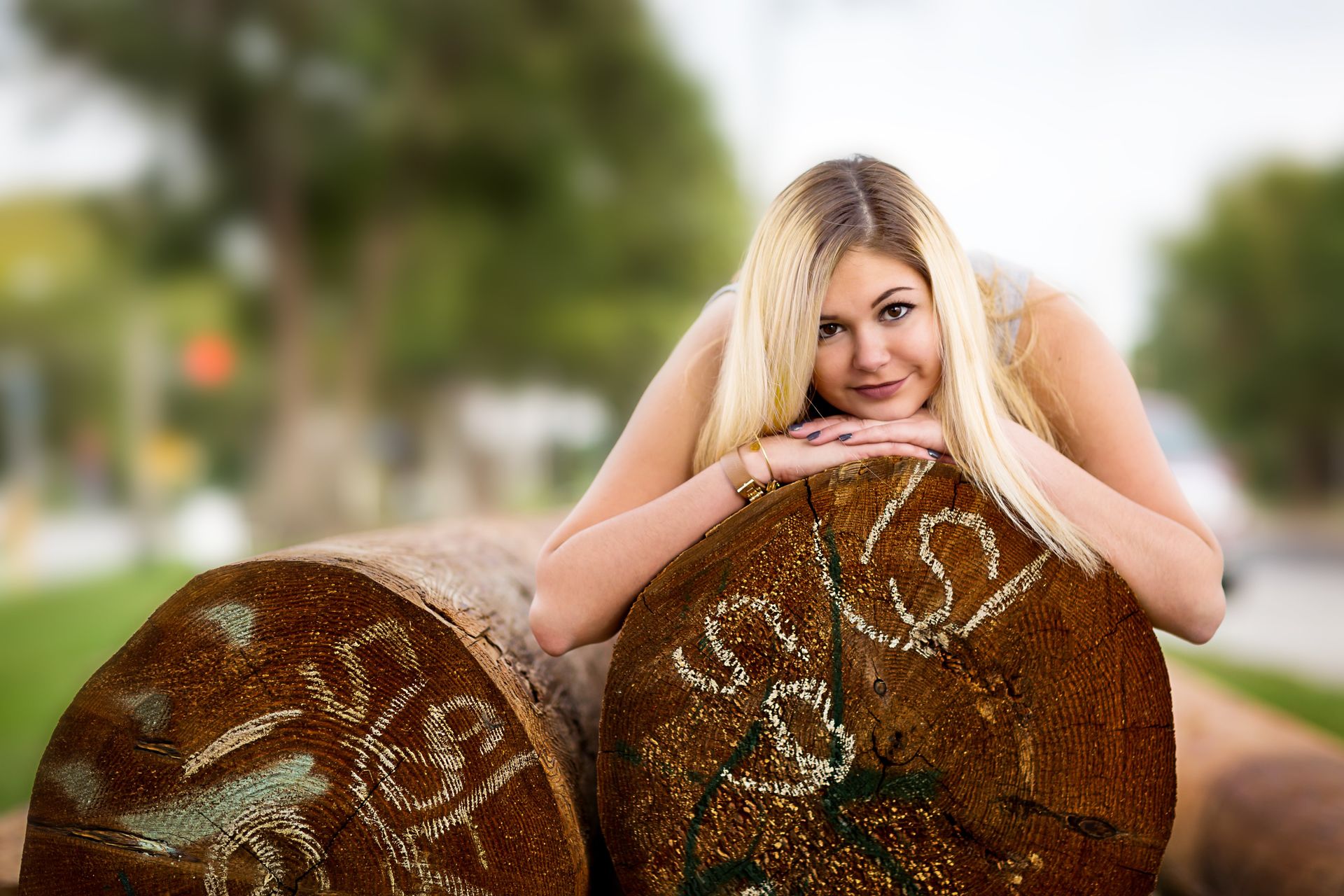 A woman is laying on a log with her head resting on it.