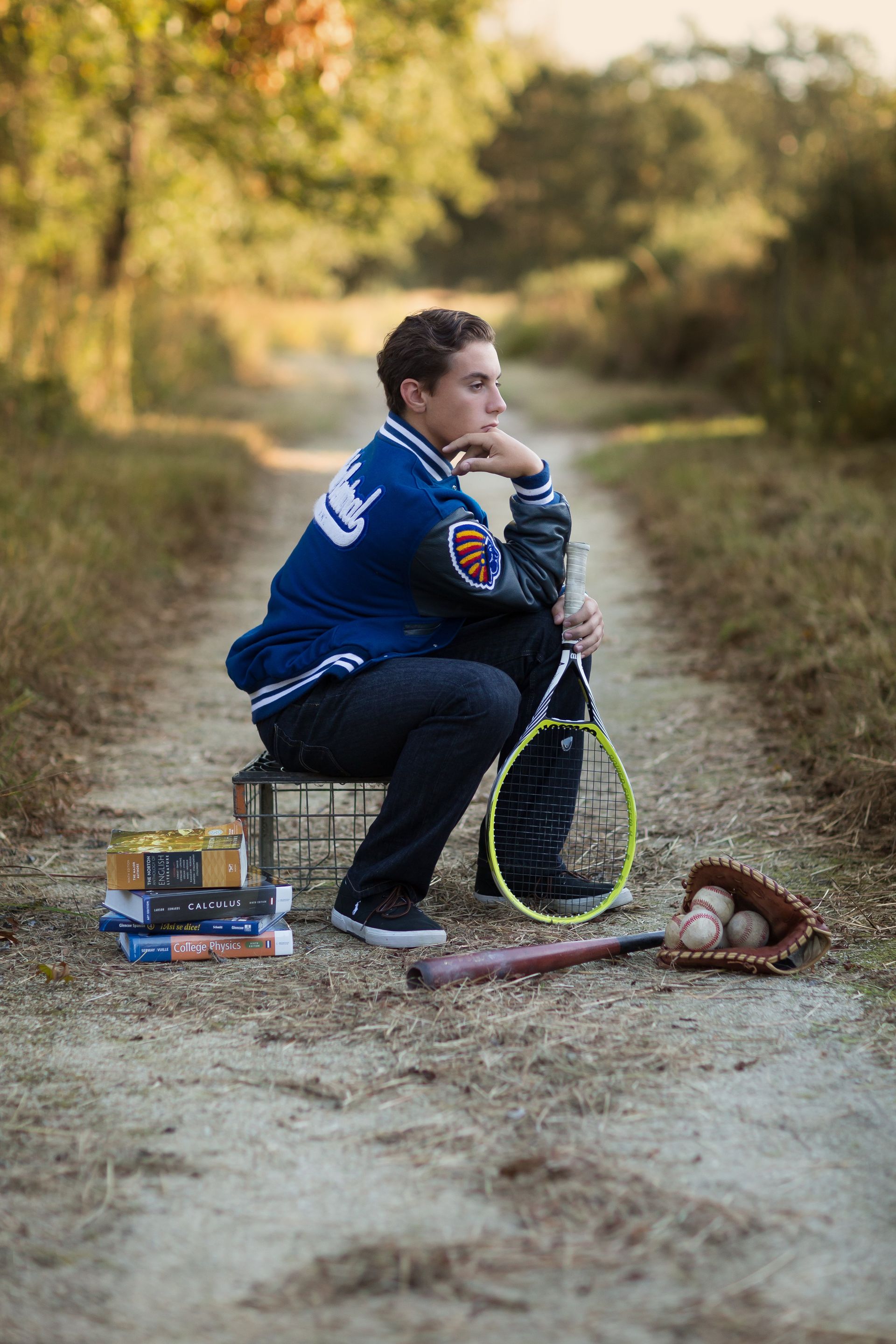 A young man is sitting on a bench holding a tennis racket.