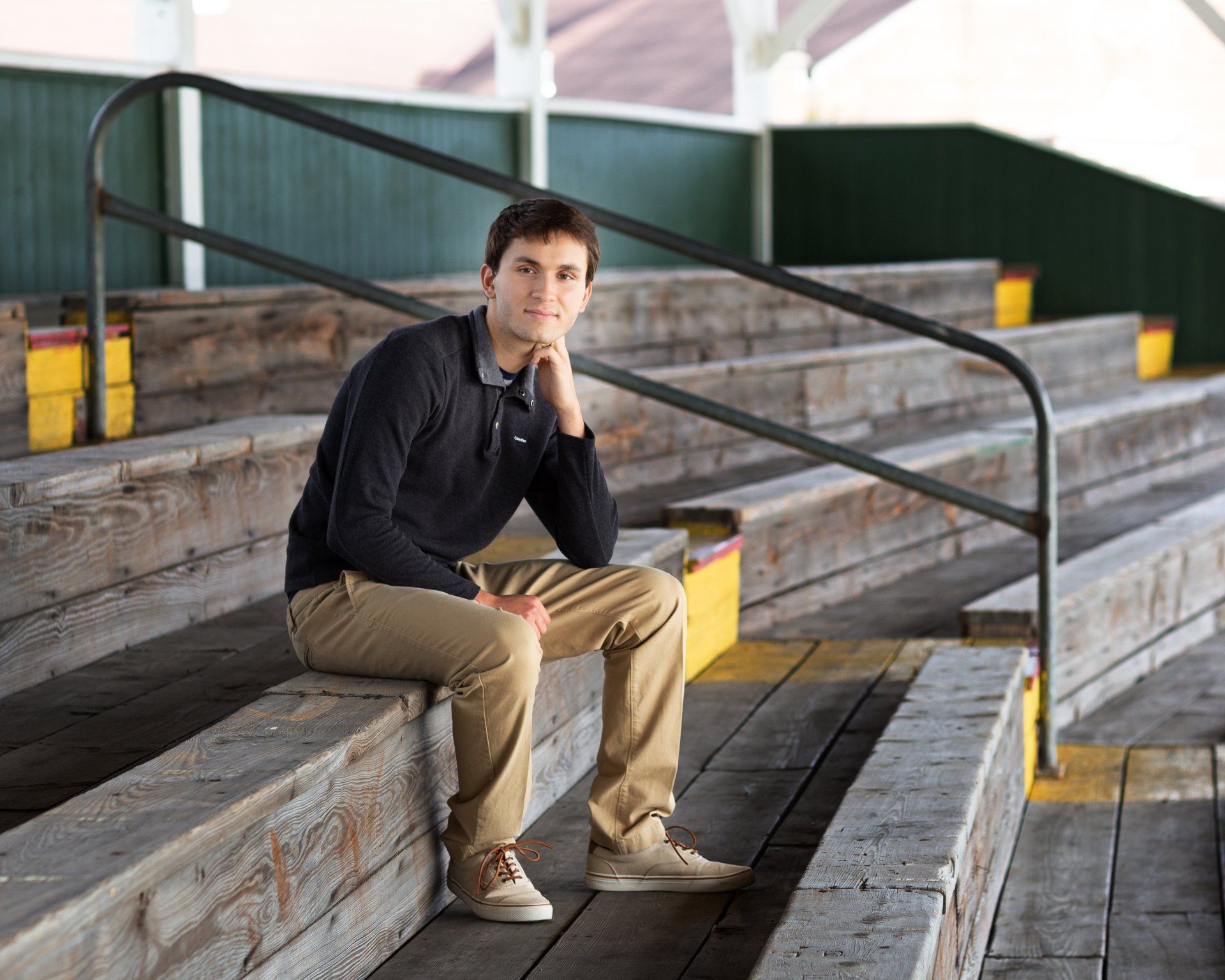 A young man is sitting on a set of wooden stairs.