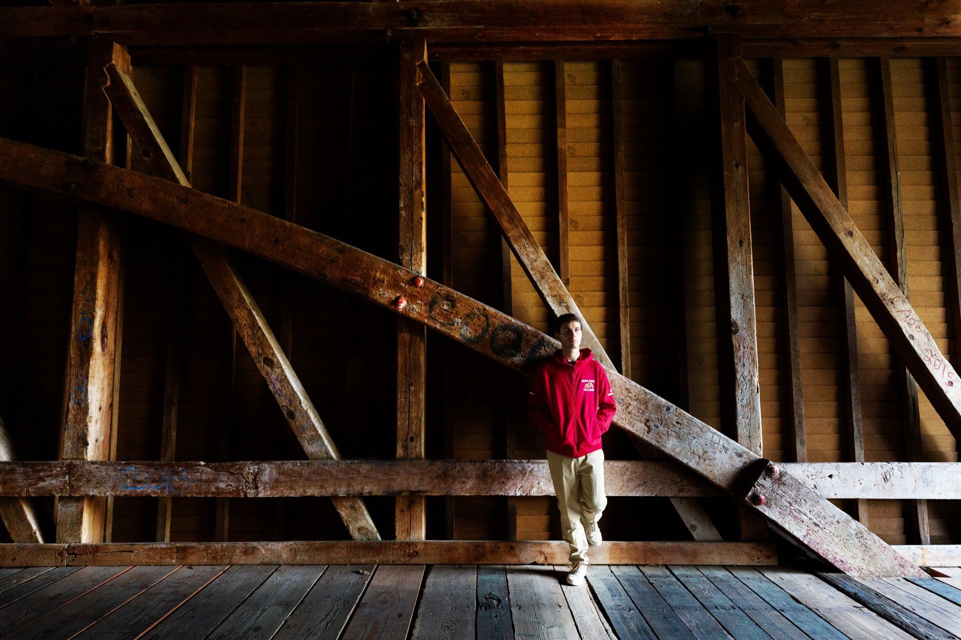 A boy in a red shirt is standing in a wooden structure