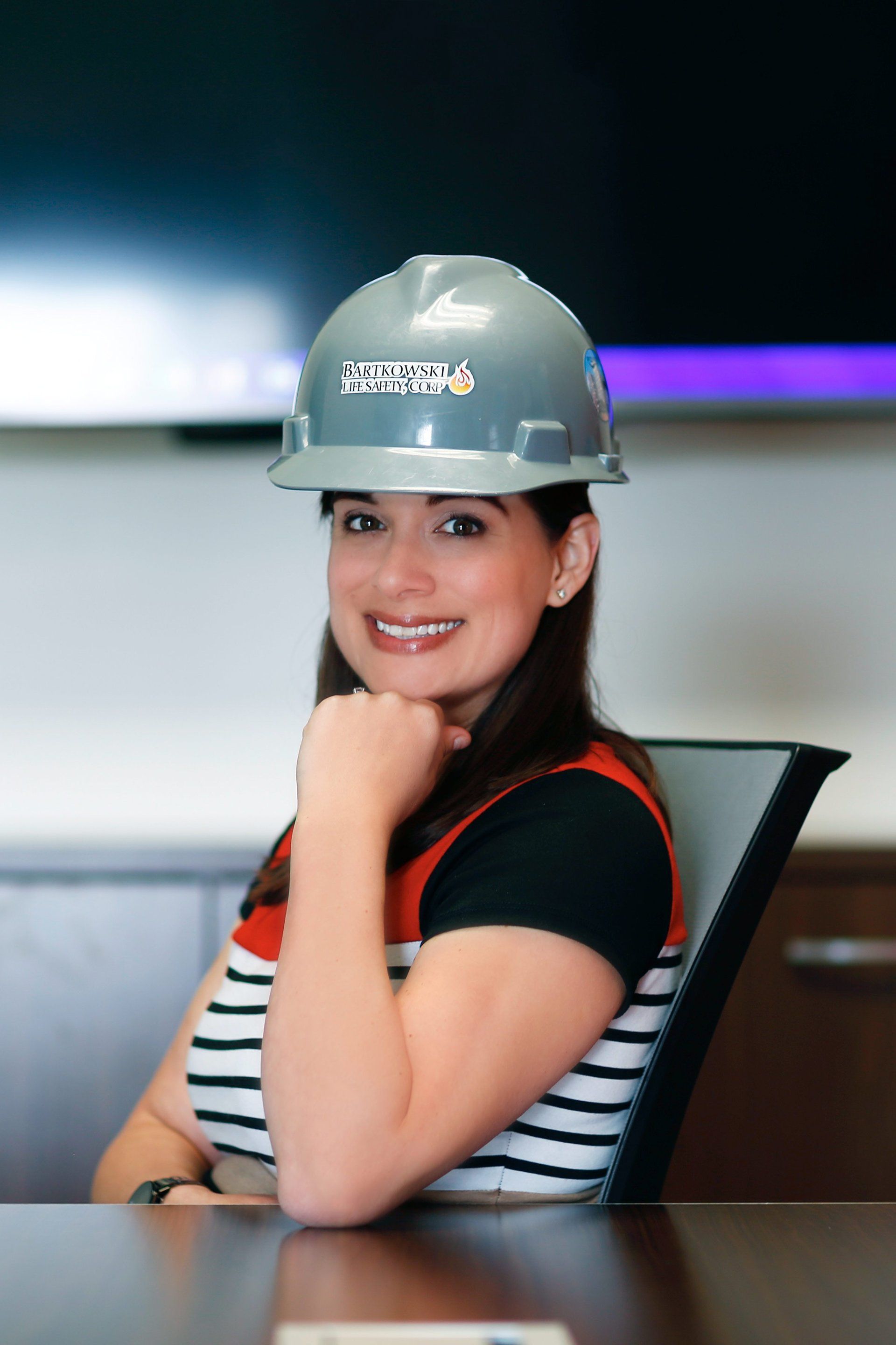 A woman wearing a hard hat is sitting at a table.