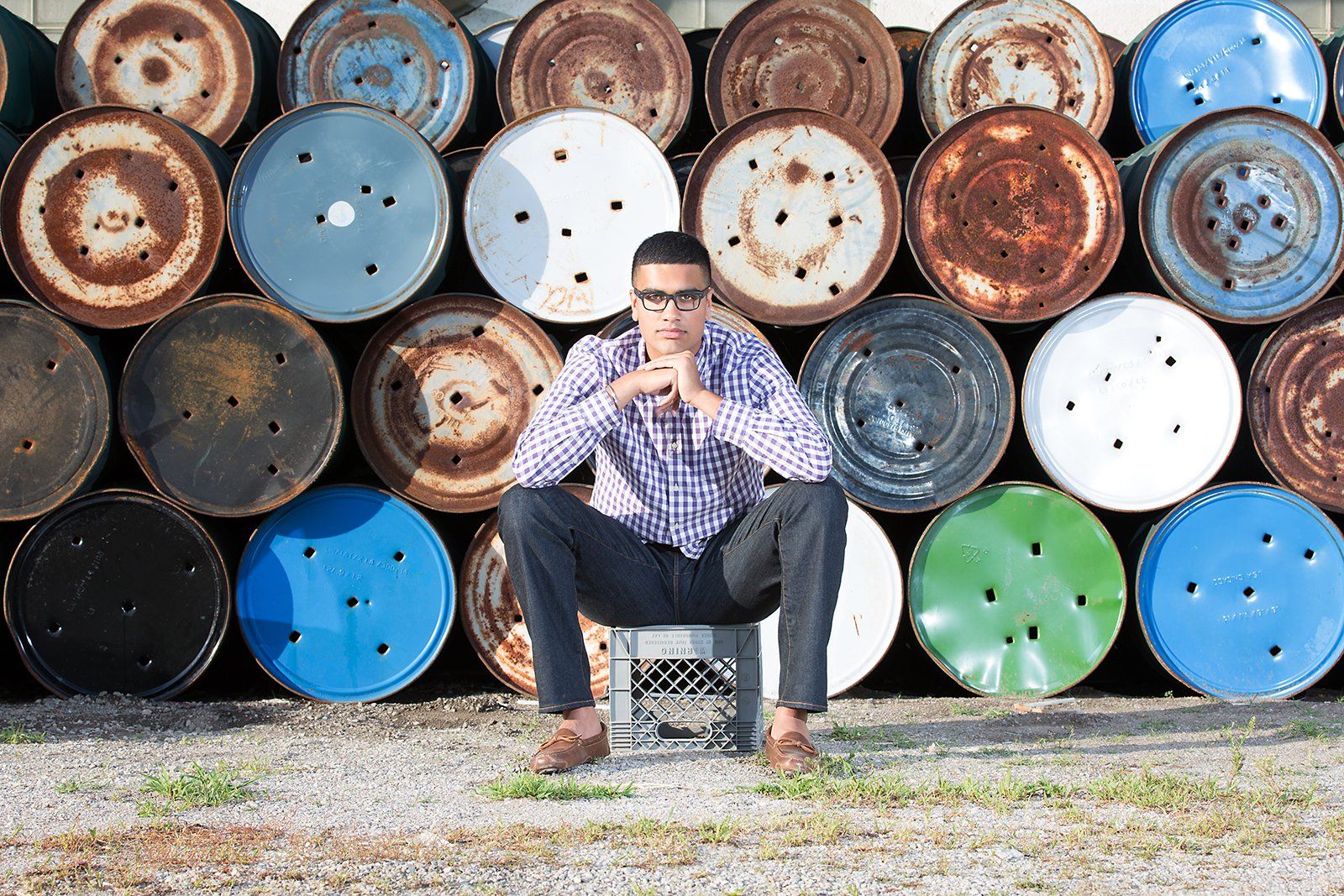 A man is sitting in front of a stack of barrels