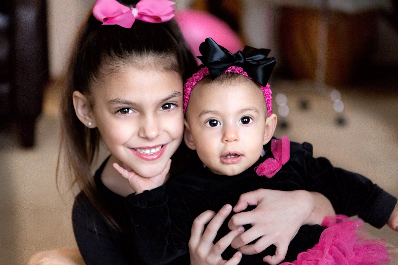 A little girl is holding a baby girl in her arms.