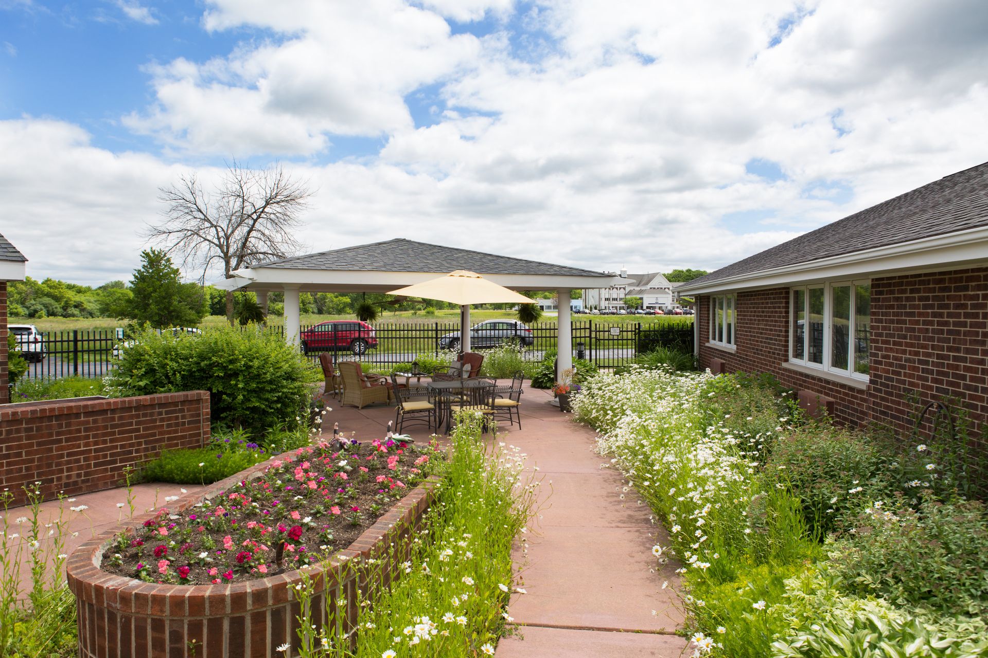 A walkway leading to a patio with a gazebo and flowers.
