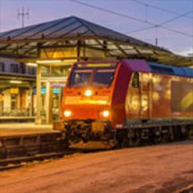 A red train is pulling into a train station at night.
