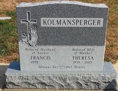 Gravestone: Francis Kolmansperger (1938-), Theresa Kolmansperger (1938-2015). Cross, flowers, 
