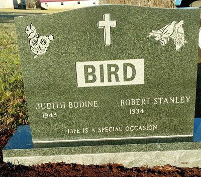 Headstone for the Bird family. Green granite with engraved name, dates, cross, doves, and a floral design.