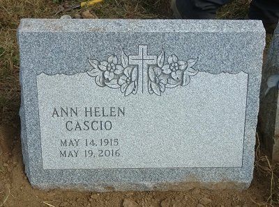 Gray granite headstone with a cross and flowers, inscribed with 