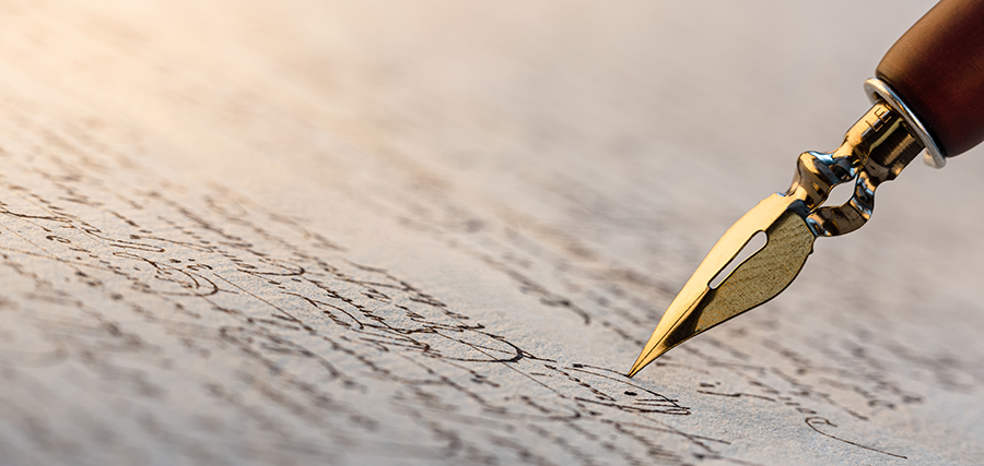 Gold-tipped pen writing on parchment with soft lighting.