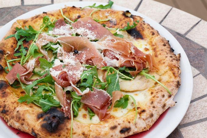 Una pizza con carne e verdure su un piatto bianco su un tavolo.