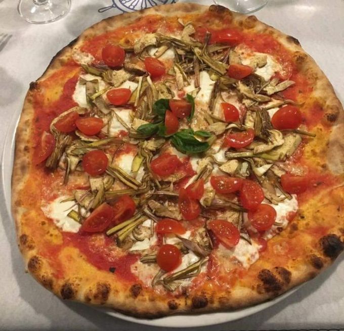 Una pizza con pomodori e funghi su un piatto bianco