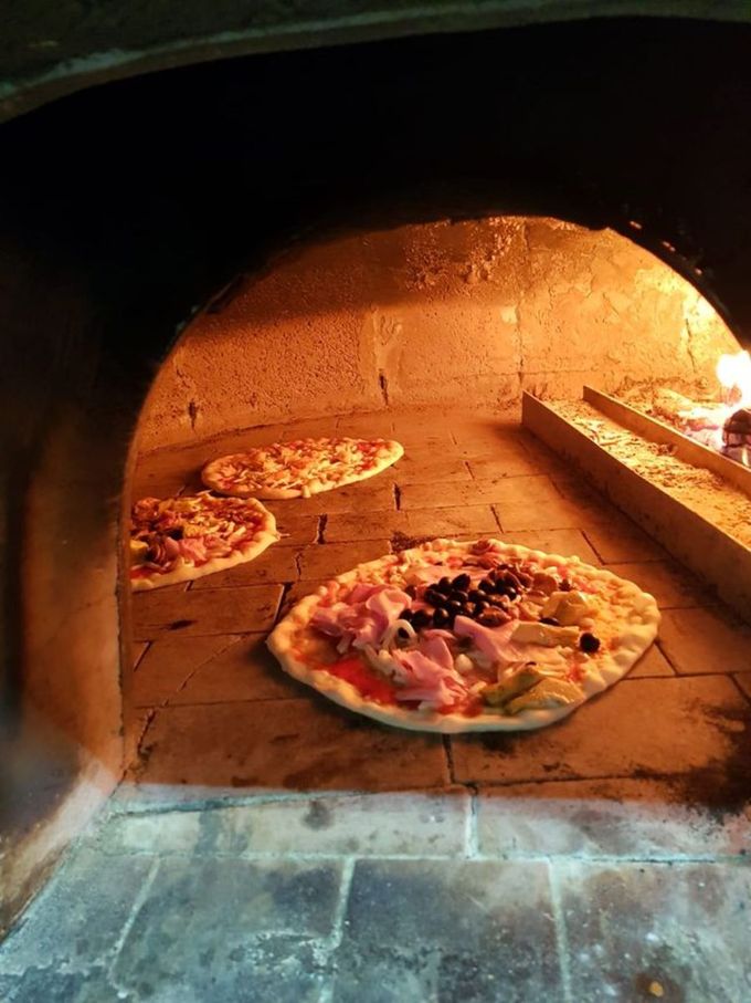 Tre pizze stanno cuocendo nel forno a legna