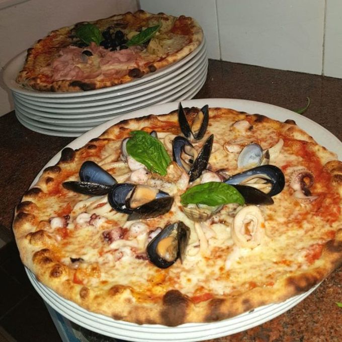 Una pizza con cozze e altri frutti di mare sopra