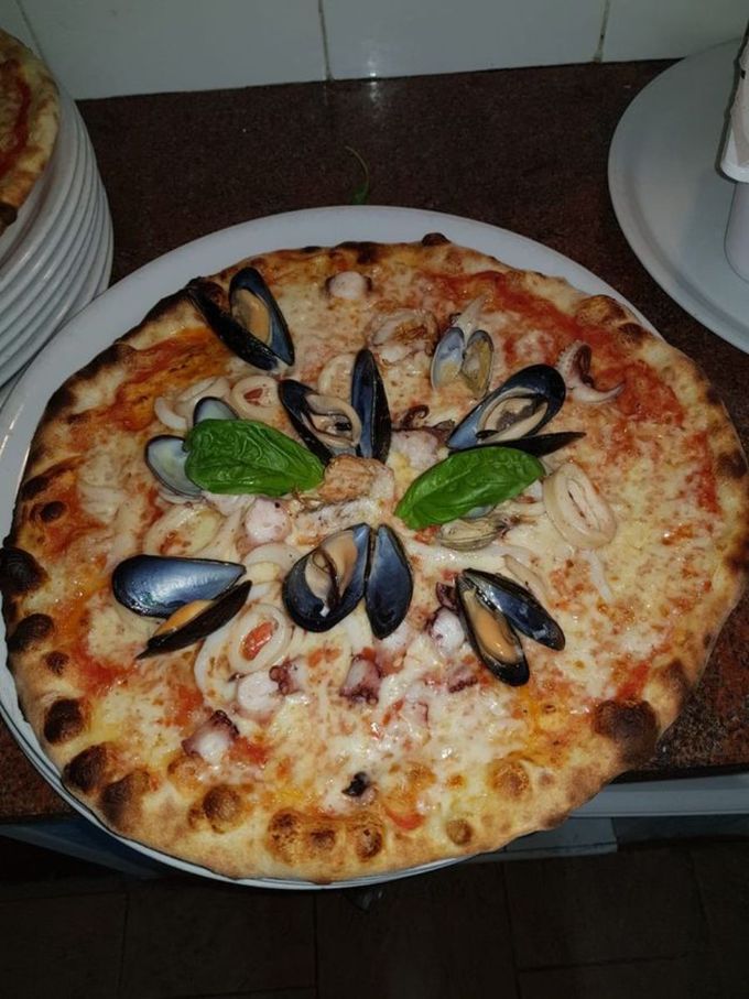 Una pizza con cozze e altri frutti di mare sopra